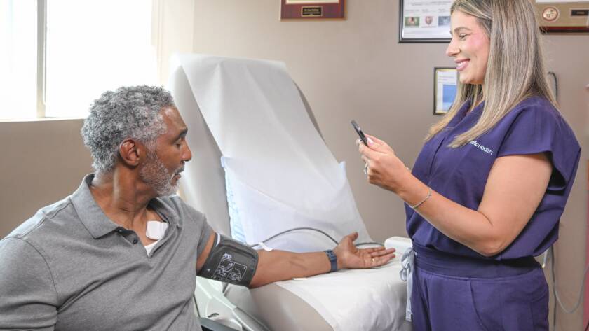 A clinician using the Vivio System with an arm cuff to non-invasively measure a patient's LVEDP in an exam room